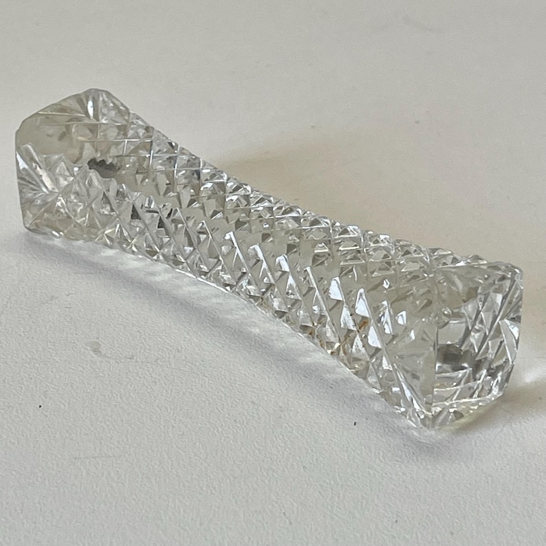 May include: A clear glass paperweight with a diamond pattern.