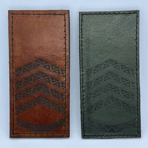 May include: Two rectangular leather patches, one in medium brown and one in dark green, each featuring a stitched border and a debossed chevron pattern consisting of three stacked V-shapes above a curved line, all centered on the surface.