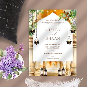 May include: A save the date wedding invitation featuring a watercolour illustration of an ornate archway adorned with flowers and lanterns. The text reads "Save the Date", "Your presence is requested at the wedding of", "Nikita and Shaan", "17th November 20XX", "From 3PM until 6PM", "103 Anywhere St, Any City", "Invitation to Follow", "RSVP", "nikitasshaan.com".