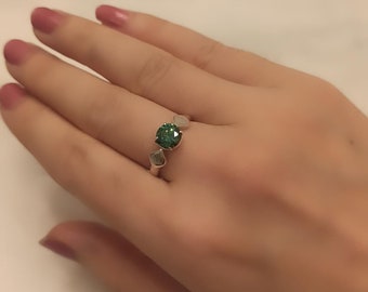 May include: A silver ring with a green gemstone in the center and two smaller silver gemstones on either side.