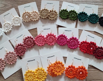 May include: Assortment of crocheted flower earrings in various colours, including white, beige, green, red, pink, orange, and yellow. The earrings are displayed on white cards with the text "Little Sparkle" on each card.