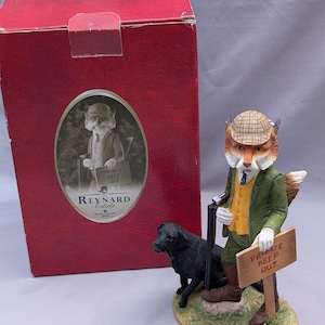 May include: A figurine of an anthropomorphic fox wearing a tweed cap, green jacket, and yellow waistcoat, holding a sign that reads PRIVATE KEEP OUT. A black dog stands beside the fox, which holds a shotgun. The item is displayed with its red box.
