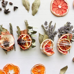 May include: A collection of dried citrus fruit, cinnamon sticks, and herbs tied together with twine. The citrus fruit is orange and grapefruit. The herbs are lavender, eucalyptus, and rosemary.