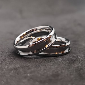 Può includere: Due fedi nuziali d'argento con un bordo smussato. Le fedi sono impilate l'una sull'altra.