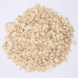 May include: A close-up of a pile of rolled oats, a common ingredient in breakfast cereals and baked goods.