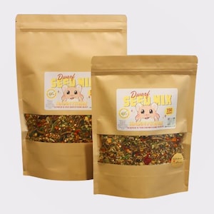 May include: Two brown paper bags filled with a mix of seeds and other ingredients for dwarf hamsters. The bags have labels that say "Dwarf Seed Mix" and feature a cartoon hamster. The smaller bag is labeled "250 grams".