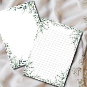 May include: Two white stationery sheets with a watercolour eucalyptus leaf design. One sheet is blank, and the other has grey horizontal lines. The leaves are green and grey, on a white fabric surface.