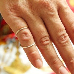 以下が含まれることがあります： 人差し指に2つの細い銀色の指輪をした手のクローズアップ