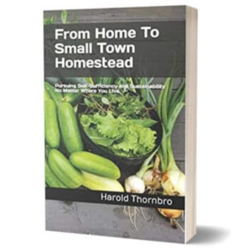 May include: A book titled From Home To Small Town Homestead: Pursuing Self-Sufficiency and Sustainability No Matter Where You Live by Harold Thornbro. The cover features a dark gray background with a bowl of fresh green lettuce and cucumbers.