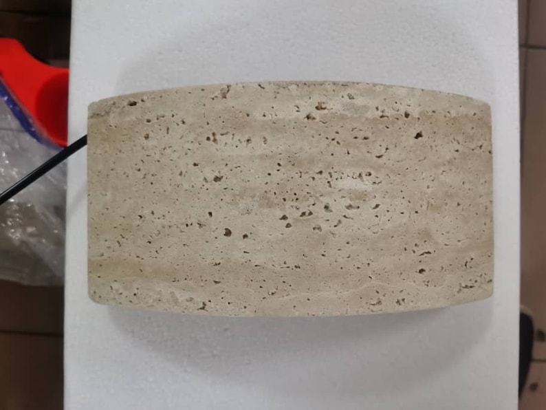 May include: A light beige, round, stone lampshade with a textured surface.