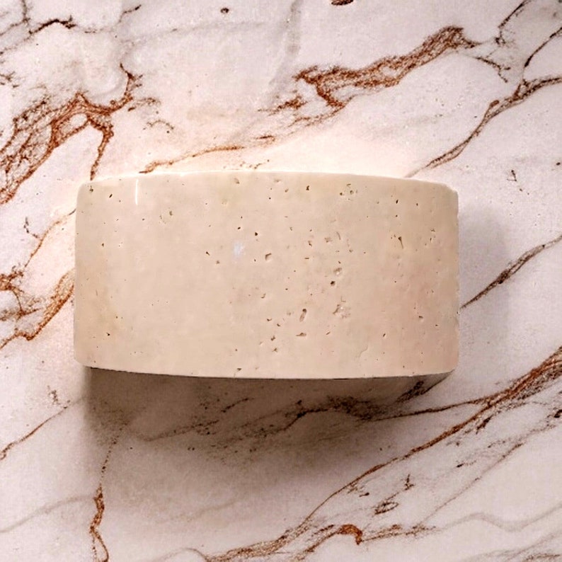 May include: A large, off-white, rectangular block of cheese with a slightly curved top. The cheese has a rough, textured surface.