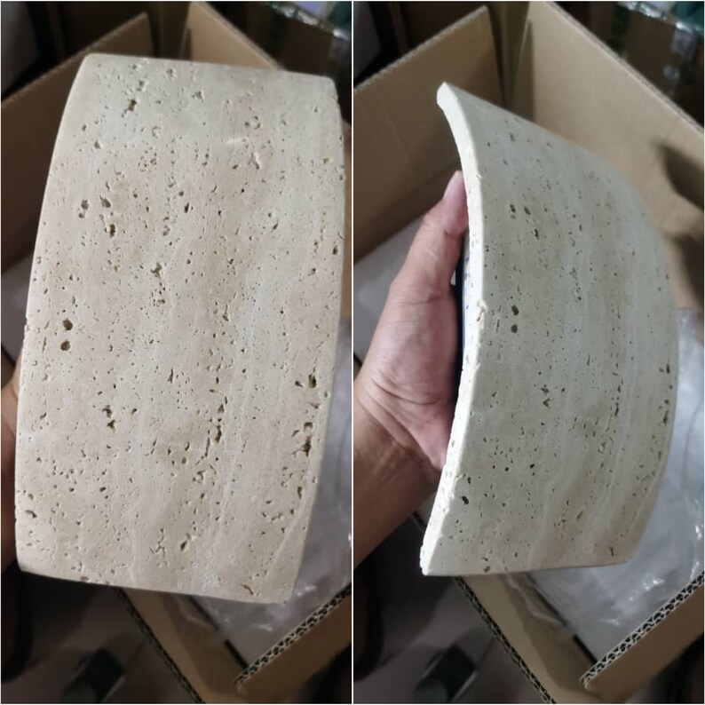 May include: A curved, light beige tile with a textured surface. The tile has a rough, uneven texture with small holes throughout.