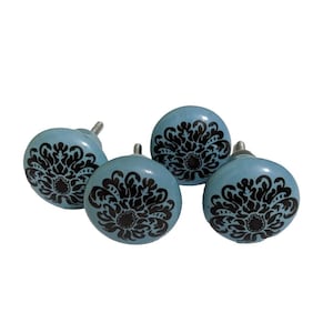 May include: Four blue ceramic cabinet knobs with black floral designs.