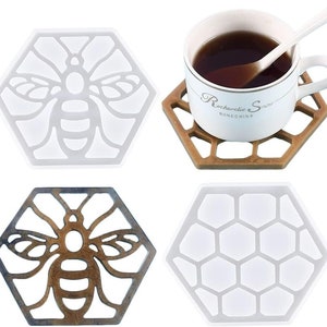 Può includere: Quattro sottobicchieri esagonali in silicone con diversi design. Due sottobicchieri presentano una silhouette di ape bianca su sfondo bianco. Un sottobicchiere presenta una silhouette di ape marrone su sfondo marrone. Un sottobicchiere presenta un motivo a nido d'ape su sfondo bianco.