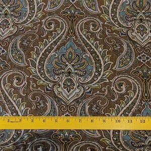May include: Brown fabric with a paisley pattern in shades of blue, green, and gold. The fabric is measured with a ruler in inches.