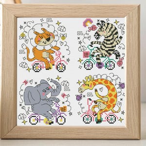 May include: A framed cross-stitch artwork with four panels of animals on bicycles. The animals are a lion, zebra, elephant, and giraffe. The artwork is in a light-coloured wooden frame. The artwork is suitable for a child's room.