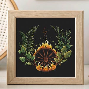 May include: Square framed art print featuring a dark background with a burning wagon wheel at the center. The wheel is surrounded by flames and greenery, including ferns and leaves. A lightning bolt is above the wheel. The frame is made of light-colored wood.