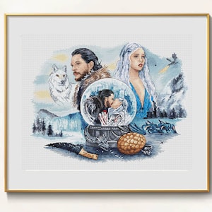 Puede incluir: Obra de arte de punto de cruz en un marco dorado con personajes de una serie de fantasía. El diseño incluye un lobo, una pareja besándose en una bola de nieve, un dragón y un huevo de dragón. La paleta de colores es principalmente azul, blanco y marrón.