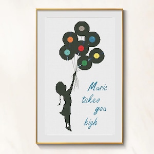 以下が含まれることがあります： 金色のフレームに入ったクロスステッチアート。風船のようにレコードを持っている人の黒いシルエット。青い筆記体で「Music takes you high」と書かれています。