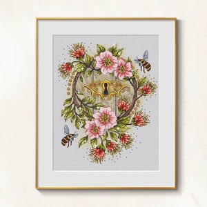 May include: Framed cross-stitch art featuring a keyhole design surrounded by pink flowers, green leaves, and red accents. Two bees are flying near the floral arrangement. The artwork is set against a light gray background.