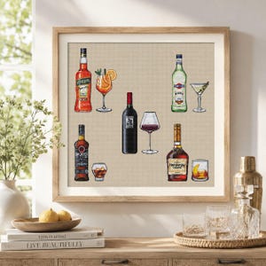 May include: A framed cross-stitch artwork on a light beige fabric background featuring six illustrated alcoholic beverages. The design includes bottles and matching glasses for Aperol, Martini, Bacardi, red wine, and Hennessy cognac, all rendered in detailed embroidery.