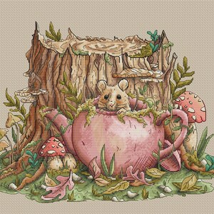 Könnte beinhalten: Ein Kreuzstich-Design mit einer Maus, die aus einer rosa Teekanne schaut. Die Teekanne ist von Pilzen, Blättern und Grün umgeben, mit einem Baumstumpf im Hintergrund. Die Farbpalette umfasst Rosa-, Braun-, Grün- und Beigetöne.