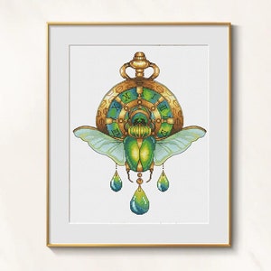 May include: Cross-stitch art of a green scarab beetle with blue wings, a gold pocket watch, and teardrop accents. The watch face features Roman numerals. The artwork is framed in a gold frame.