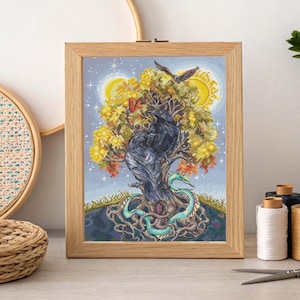 May include: A framed cross-stitch artwork featuring two black ravens perched on a tree with yellow and orange leaves. A teal serpent coils around the tree's roots. The background shows a starry sky with a sun and moon.
