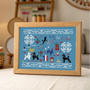 May include: A framed cross-stitch with a blue background, depicting French symbols. The design includes poodles, the Eiffel Tower, a rooster, and the French flag. The words "Vive La France" are also included in the design.