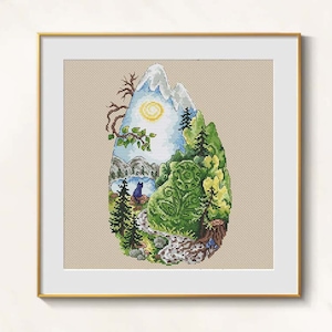 May include: Cross-stitch art of a mountain landscape within a teardrop shape. The artwork features a snow-capped mountain, a lake, trees, and a sun. The color palette includes shades of green, blue, and white, framed in a gold frame.