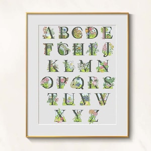 Puede incluir: Una impresión artística del alfabeto enmarcada. Cada letra del alfabeto está decorada con flores y vegetación coloridas. Las letras son de color verde oscuro y la obra de arte está enmarcada en un marco dorado.