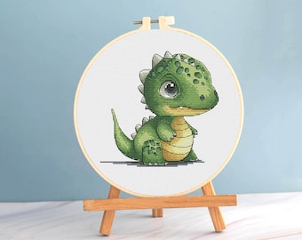 Può includere: Ricamo a punto croce di un dinosauro dei cartoni animati in un cerchio di legno. Il dinosauro è verde con la pancia gialla e grandi occhi espressivi. Il cerchio è esposto su un piccolo cavalletto di legno.