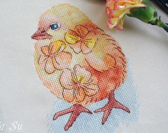 May include: Cross-stitch design of a yellow and orange chick with three flower accents. The chick has a blue eye and pink feet. The background is a light blue color. The design is on a white fabric.