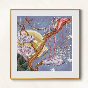 Puede incluir: Arte de punto de cruz en un marco dorado que representa a una persona leyendo en una rama de árbol bajo la luna llena. La obra presenta un cielo nocturno, nubes, estrellas y el texto "BOOKS are magic."