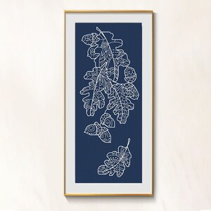 May include: A framed print featuring a white line drawing of oak leaves and acorns on a navy blue background. The artwork is encased in a gold frame, creating a striking contrast. The detailed botanical illustration adds a touch of nature-inspired decor.
