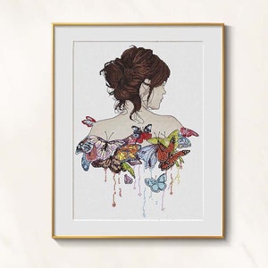 May include: Cross-stitch art print featuring a woman's silhouette from the back, with her hair up. Colorful butterflies are stitched on her back and shoulders, with some trailing below. The artwork is framed in a gold-colored frame.