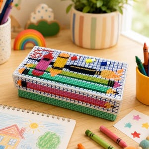 Può includere: Una scatola rettangolare in tela plastica con un disegno a punto croce di matite colorate su sfondo a griglia. Il coperchio presenta un motivo con matite rosse, gialle e verdi, mentre la base è di colore verde chiaro.