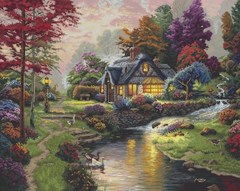 May include: A cross-stitch landscape depicts a cottage with lit windows nestled among colorful trees and flowers. A stream flows in the foreground, reflecting the warm light. Swans and ducks swim in the water, and a path leads to the cottage.