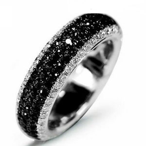 May include: A silver band ring with a row of black diamonds and a row of white diamonds.
