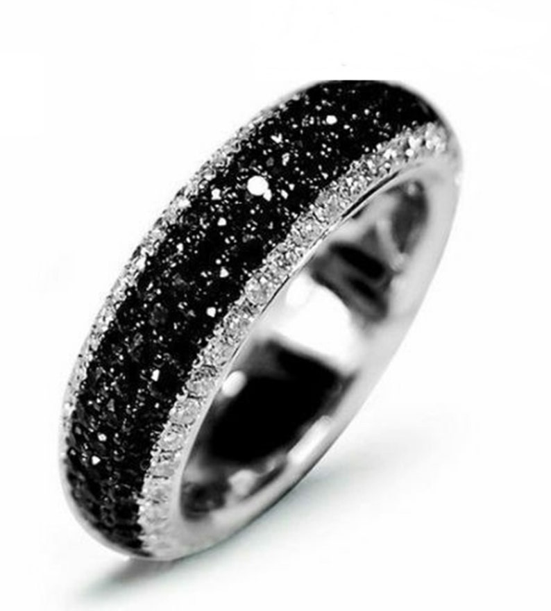 May include: A silver band ring with a row of black diamonds and a row of white diamonds.