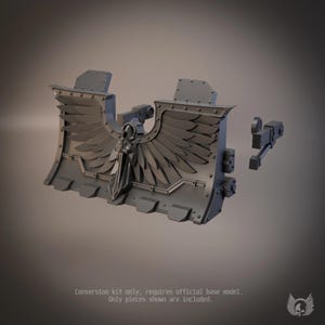 May include: A dark gray resin conversion kit for a miniature vehicle, featuring a large plow blade with a central winged sword emblem and rivet details. The text on the image reads: Conversion kit only, requires official base model. Only pieces shown are included.
