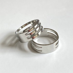 May include: Two silver rings with a cut-out design. The rings are stacked on top of each other.