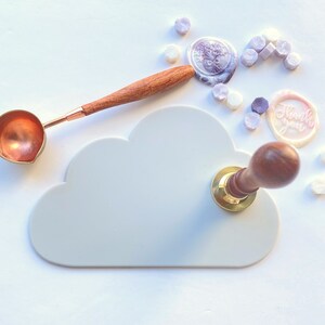 May include: A white cloud-shaped silicone mat with a wooden and gold wax seal stamp on top. The mat is surrounded by purple and white wax seals, including one that says "Thank you".