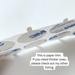 May include: A sheet of 3M double-coated tissue adhesive circles. The circles are white and have a blue 3M logo. The text "Double Coated Tissue" and "9448A" are printed on the sheet. This is paper thin. If you need thicker ones, please check out my other listing.