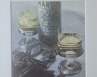 May include: A vintage advertisement for Martini Extra Dry vermouth. The ad features a bottle of Martini vermouth, two glasses filled with the drink, and ice cubes. The text reads "Frozen Assets. Winter just wouldn't be the same without ice. Nor would Martini Dry. Because ice enhances the clean, subtle taste of Martini's unique blend of fine herbs and wines. Ice and Martini simply belong together. And we'll drink to that. Martini Extra Dry: The right one. Just by itself."