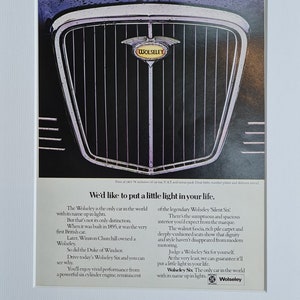 Puede incluir: Un anuncio vintage en blanco y negro para el automóvil Wolseley Six. El anuncio presenta un primer plano de la parrilla cromada del automóvil con el logotipo de Wolseley. El texto dice "We'd like to put a little light in your life." y "The Wolseley Six. The only car in the world with its name up in lights."