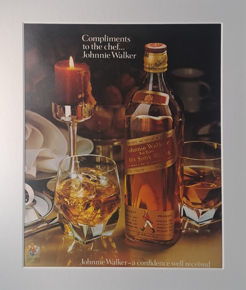 Op de afbeelding: Een advertentie voor Johnnie Walker Red Label Scotch Whisky. De afbeelding toont een fles whisky, twee glazen whisky met ijs en een brandende kaars. De tekst luidt "Compliments to the chef... Johnnie Walker" en "Johnnie Walker - a confidence well received."