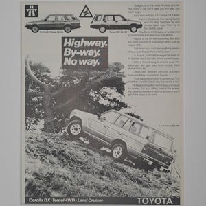 May include: An advertisement for Toyota vehicles, featuring three different models: a Corolla DX Estate, a Tercel 4WD, and a Land Cruiser. The ad includes the text "Highway. By-way. No way." and mentions the vehicles' features and capabilities.