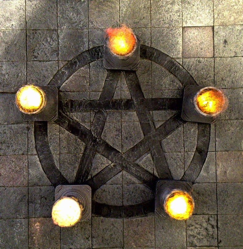 May include: A dark gray pentagram design with five illuminated torches. The torches have a square base and emit a bright yellow-orange light. The background is a textured, gray stone surface.