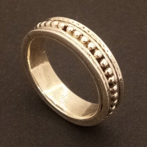 Può includere: Un anello d'argento con una fascia di perline. La fascia è realizzata con piccole perline rotonde che sono equidistanti.
